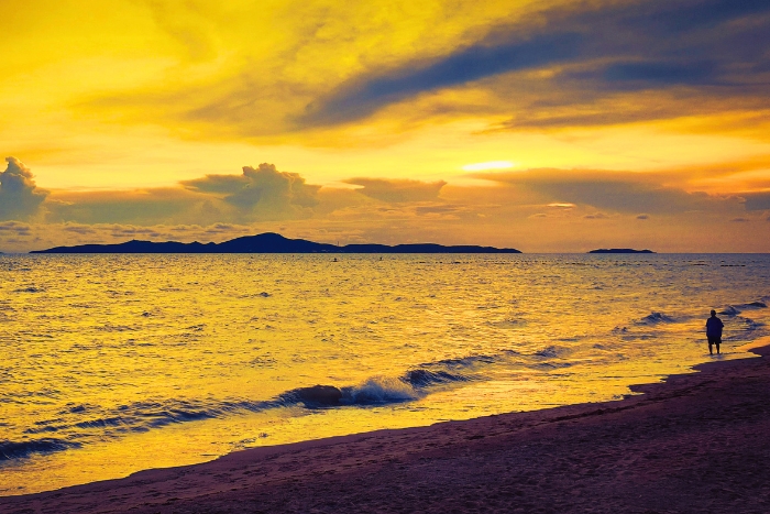 Ocean waves glowing under a tropical sunset