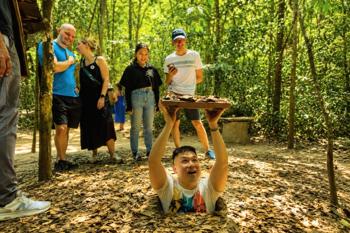 Squeezing into a camouflaged trapdoor at the Cu Chi Tunnels